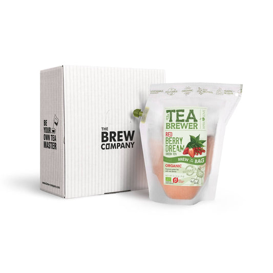 Verpackter Red Berry Dream Teabrewer mit grünem Tee und roten Beeren neben einer weißen Brew Company Geschenkbox